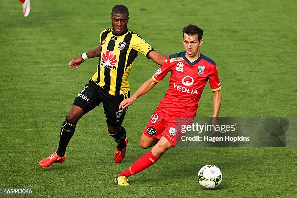 Isaias of Adelaide United runs the ball under pressure from Roly Bonevacia of the Phoenix during the round 20 A-League match between the Wellington...