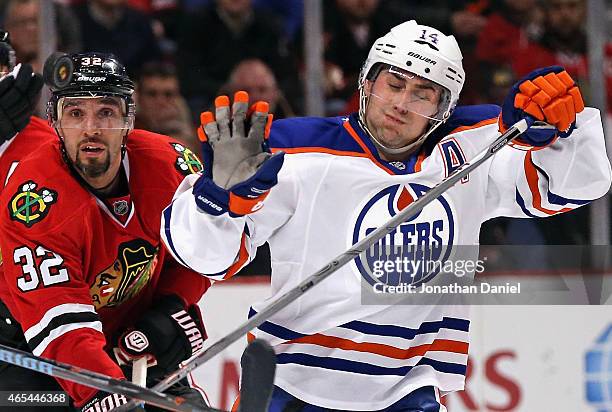 Michal Rozsival of the Chicago Blackhawks and Jordan Eberle of the Edmonton Oilers try to avoid a puck in the air at the United Center on March 6,...