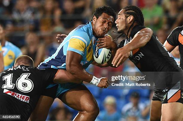 Agnatius Paasi of the Titans is tackled by Matthew Lodge and Martin Taupau of the Tigers during the round one NRL match between the Gold Coast Titans...