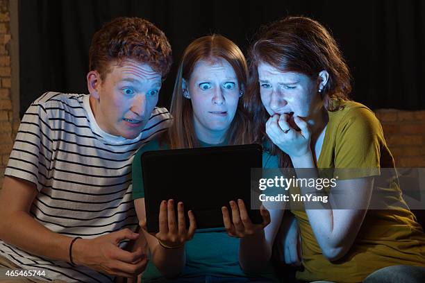 terrified young adults streaming scary movie on digital tablet computer - surprised woman looking at tablet stock pictures, royalty-free photos & images
