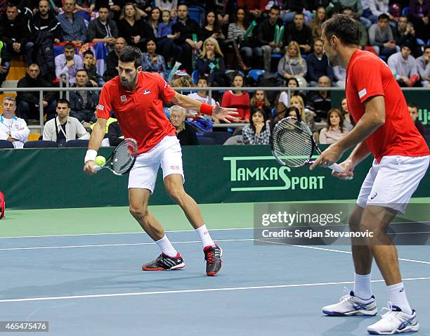 Novak Djokovic and Nenad Zimonjic of Serbia in action against Marin Draganja and Franko Skugor of Croatia during their men's double match on the day...