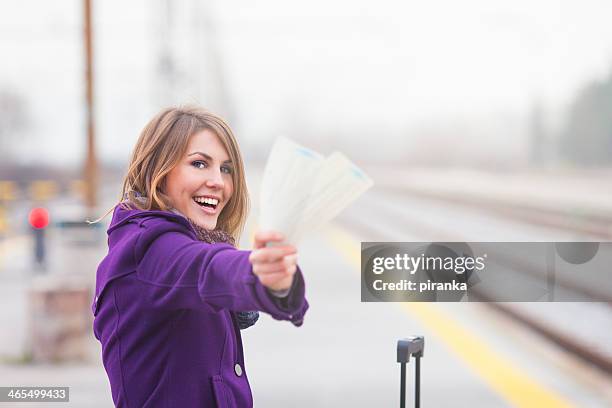 smiling female traveler at railroad station with tickets - train ticket stock pictures, royalty-free photos & images