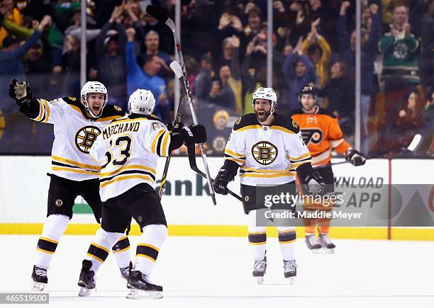 Ryan Spooner and Maxime Talbot congratulate Brad Marchand of the Boston Bruins after he scored the game winning goal in overtime against the...