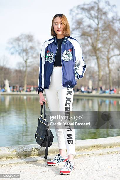 Ponthip Chaimuttayompol poses wearing a N.U.D.E. Jacket, Something Boudoir pants, New Balance shoes and Givenchy bag on Day 5 of Paris Fashion Week...