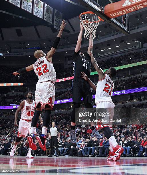 Kevin Love of the Minnesota Timberwolves rebounds over Taj Gibson and Jimmy Butler of the Chicago Bulls at the United Center on January 27, 2014 in...