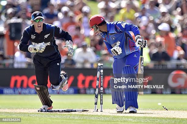 Afghanistan's batsman Usman Ghani is bowled by New Zealand bowler Daniel Vettori as New Zealand wicketkeeper Luke Ronchi celebrates during the Pool A...