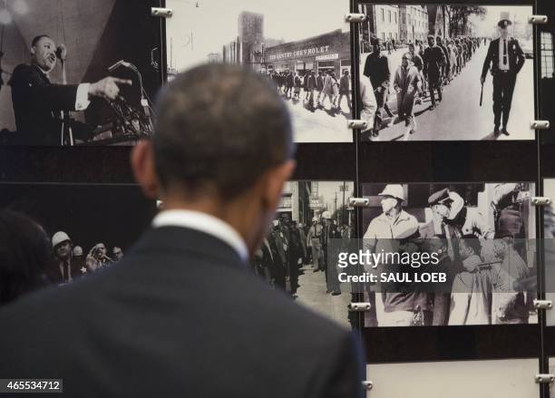 President Barack Obama looks at photos of the original march in Selma during a tour of the National Voting Rights Museum to mark the 50th Anniversary...