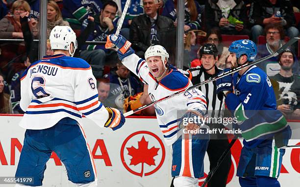 Jason Garrison of the Vancouver Canucks watches Ryan Smyth of the Edmonton Oilers celebrate the game-winning goal scored by Jesse Joensuu of the...