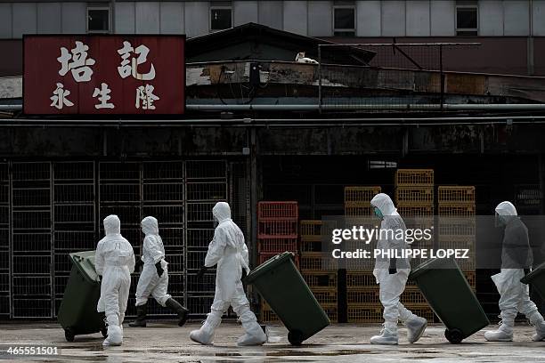 Officials wearing masks and protective suits dispose of culled dead chickens in Hong Kong on January 28 as Hong Kong began a mass cull of 20,000...