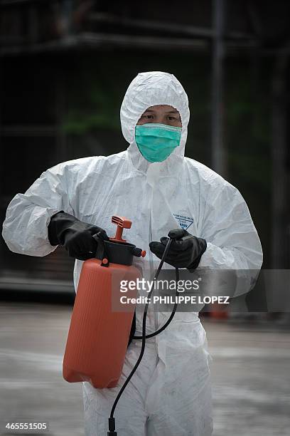 An official wearing a mask and protective suit carries a disinfectant container in Hong Kong on January 28 as Hong Kong began a mass cull of 20,000...