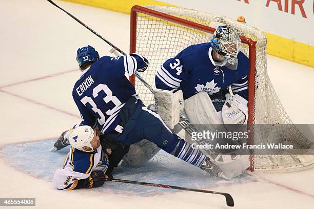 Tim Erixon of the Toronto Maple Leafs holds back Olli Jokinen of the St. Louis Blues from sliding into his teams goalie James Reimer during third...