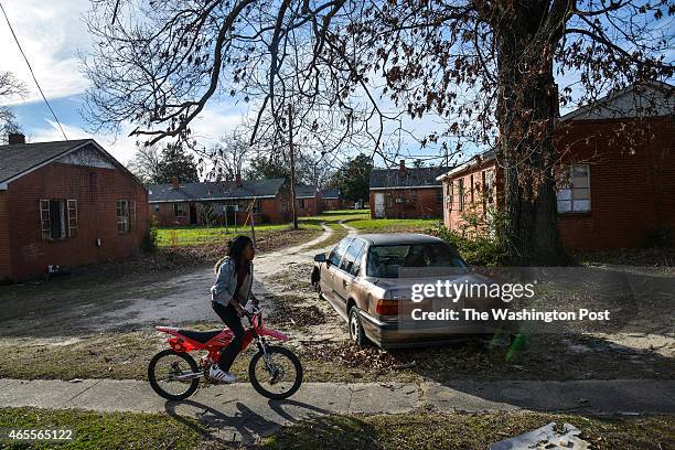 Monique Randall L, rides her bike through her neighborhood after school in the Minnie B. Anderson Homes neighborhood, a dilapidated housing complex...