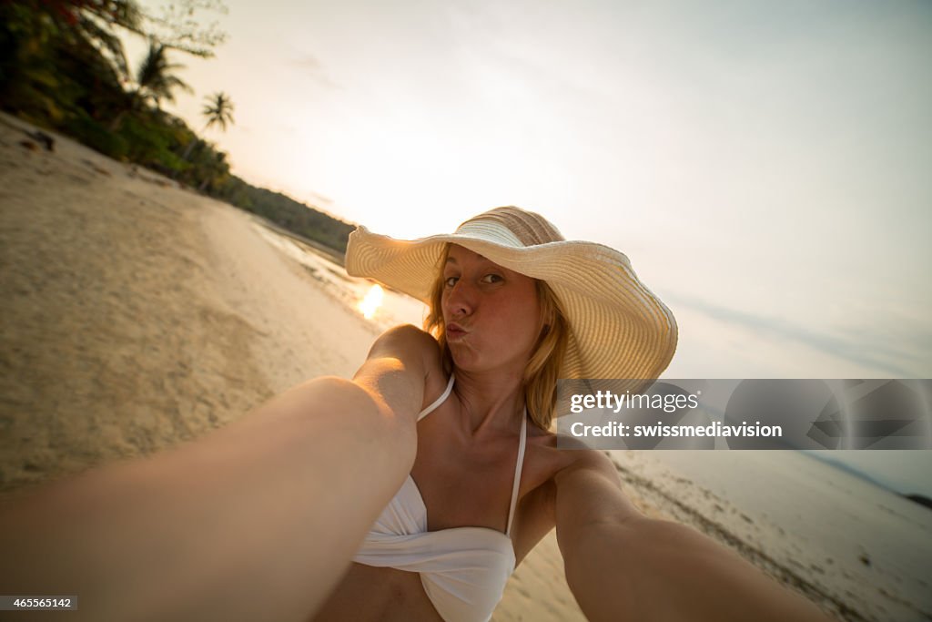 Linda mujer en la playa de tomar un selfe