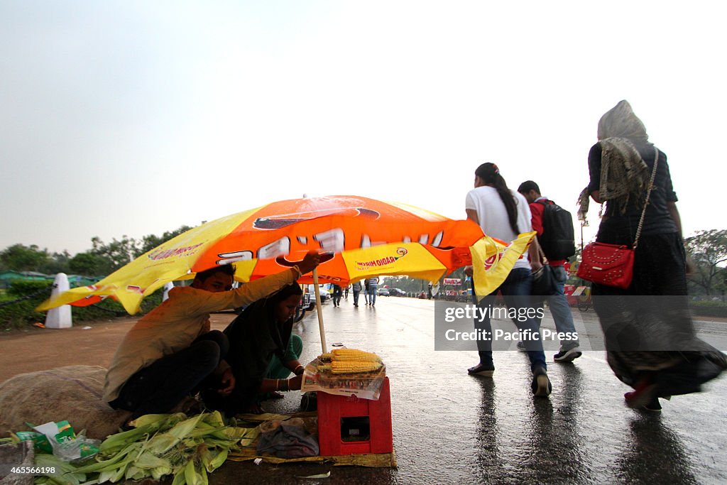 An Indian Women shields herself from rain with a plastic...