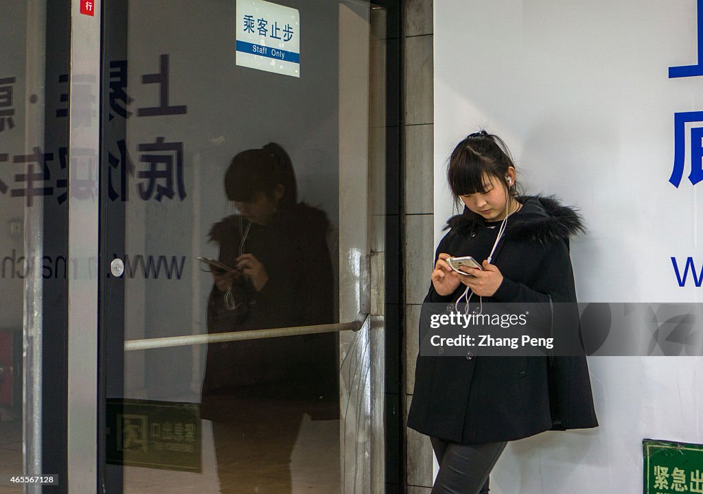 Passengers read their smart phones while waiting for the...
