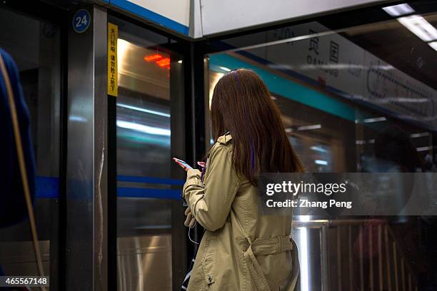 Passengers read their smart phones while waiting for the subway train. People who have the smartphone-addict nowadays are called Smartphone zombies.