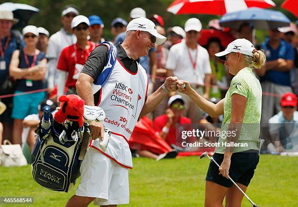 Stacy Lewis of the United States celebrates with her caddy Travis Wilson after saving par on the 12th hole during the final round of the HSBC Women's...