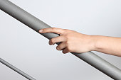 Hand holding a gray matte handrail going up, gray background