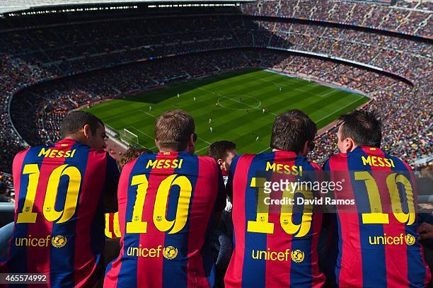 Barcelona supporters wearing Lionel Messi shirts watch the game from the stands during the La Liga match between FC Barcelona and Rayo Vallecano de...
