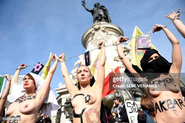 Femen leader Inna Shevchenko and other bare-chested activists of the feminist movement raise their hands symbolically chained together with religious...