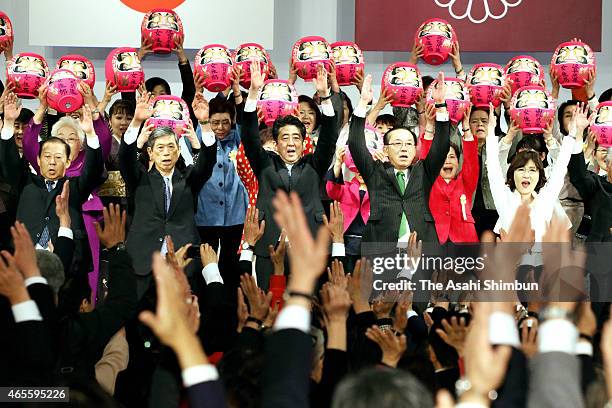 Japanese Prime Minister and president of the ruling Liberal Democratic Party Shinzo Abe and other members cheer with Daruma dolls in pray for wins at...