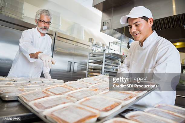 volunteer chefs preparing frozen meals for food bank - frozen food stock pictures, royalty-free photos & images