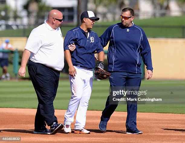 Jose Iglesias of the Detroit Tigers is helped off the field by Tigers trainers Doug Teter and Corey Tremble after being hit in the leg with a...