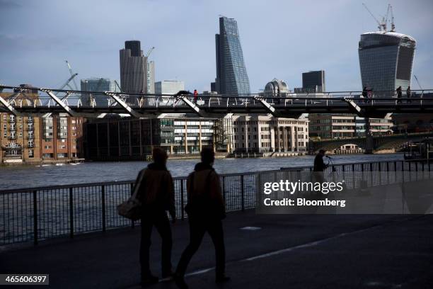 Pedestrians walk along the south bank of the River Thames as Tower 42, left, the Leadenhall building, also known as the 'Cheesegrater,' center, and...