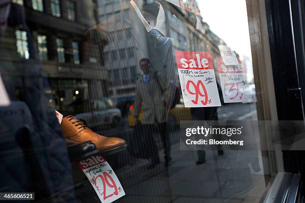 Pedestrians are reflected in the window display of a mens' clothes store in London, U.K., on Tuesday, Jan. 28, 2014. The U.K. Economy expanded 0.7...