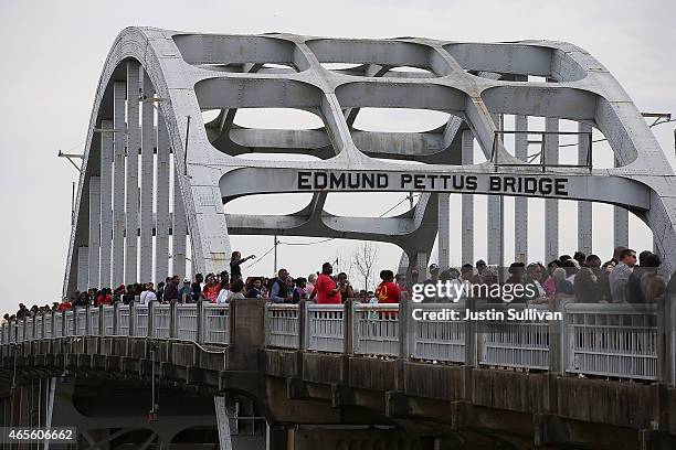 Thousands of people walk across the Edmund Pettus Bridge during the 50th anniversary commemoration of the Selma to Montgomery civil rights march on...