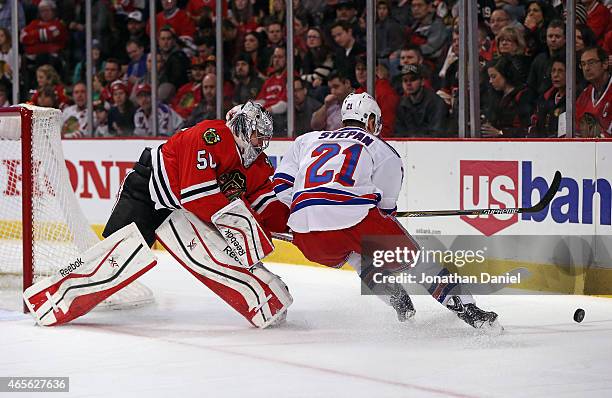Corey Crawford of the Chicago Blackhawks knocks the puck away from Derek Stepan of the New York Rangers at the United Center on March 8, 2015 in...