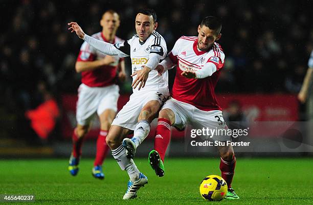 Fulham forward Clint Dempsey is challenged by Leon Britton of Swansea during the Barclays Premier League match between Swansea City and Fulham at...