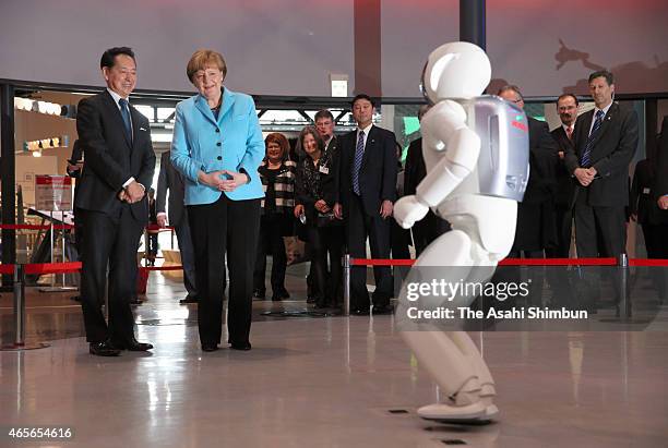 German Chancellor Angela Merkel and former astronaut and museum chief Mamoru Mori watch the humanoid robot Asimo of Honda Motor Co performance during...