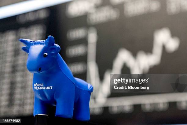 Toy bull figurine sits on a trader's computer screen as the DAX Index curve sits on a board beyond at the Frankfurt Stock Exchange in Frankfurt,...