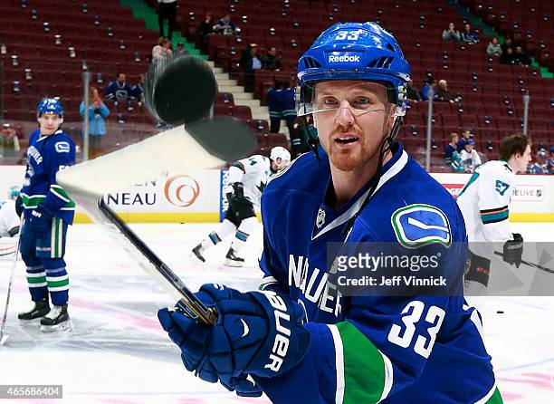 Luca Sbisa of the Vancouver Canucks and Joe Pavelski of the San Jose Sharks watch a loose puck during their NHL game at Rogers Arena March 3, 2015 in...