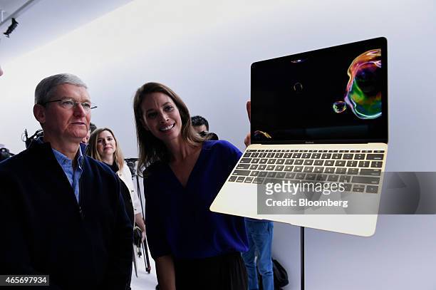 Tim Cook, chief executive officer of Apple Inc., left, views the new Macbook laptop with model Christy Turlington Burns at the Apple Inc. Spring...
