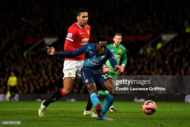 Danny Welbeck of Arsenal scores his team's second goal despite the attentions from Chris Smalling of Manchester United during the FA Cup Quarter...