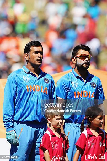 Dhoni of India and Virat Kohli of India sing the national anthem prior to the 2015 ICC Cricket World Cup match between Ireland and India at Seddon...