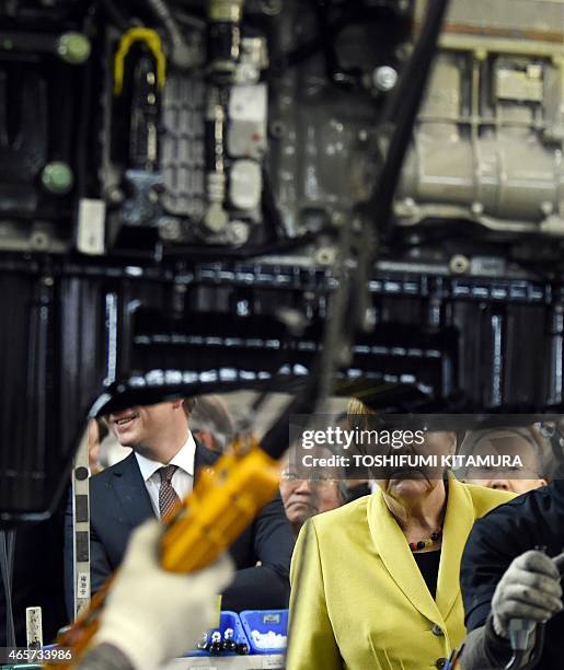 German Chancellor Angela Merkel watches workers mounting an engine onto a chassis during a visit to the Mitsubishi Fuso Truck and Bus Corporation...