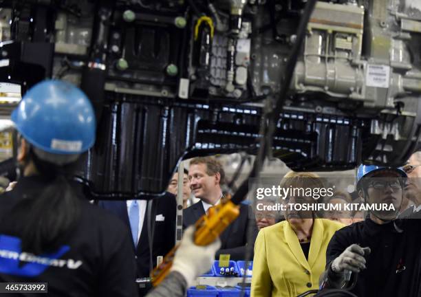 German Chancellor Angela Merkel watches workers mounting an engine onto a chassis during a visit to the Mitsubishi Fuso Truck and Bus Corporation...