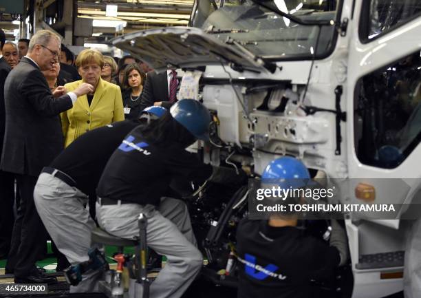 German Chancellor Angela Merkel watches workers mounting a cabin onto a chassis during a visit to the Mitsubishi Fuso Truck and Bus Corporation...