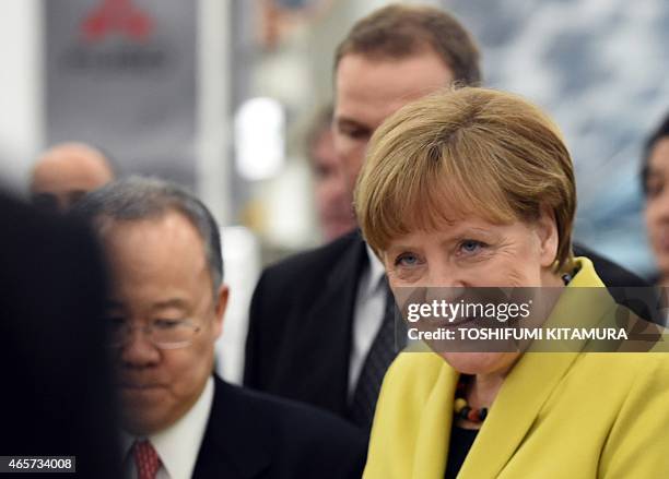 German Chancellor Angela Merkel greets employees of the Mitsubishi Fuso Truck and Bus Corporation during a visit to their Kawasaki plant in Kawasaki...