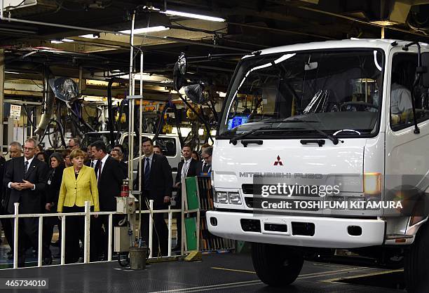 German Chancellor Angela Merkel watches a truck moving off from the assembly line during a visit to the Mitsubishi Fuso Truck and Bus Corporation...