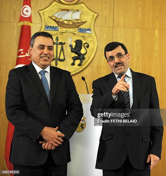 Tunisia's new Prime minister Mehdi Jomaa stands next to his predecessor Ali Laarayedh during a handover ceremony in Tunis on January 29, 2014....