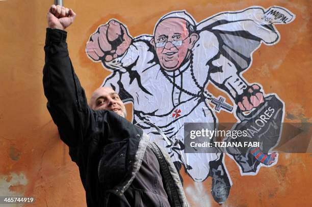 Italian street artist Maupal poses next to his street art mural showing Pope Francis as a superman, flying through the air with his white papal cloak...