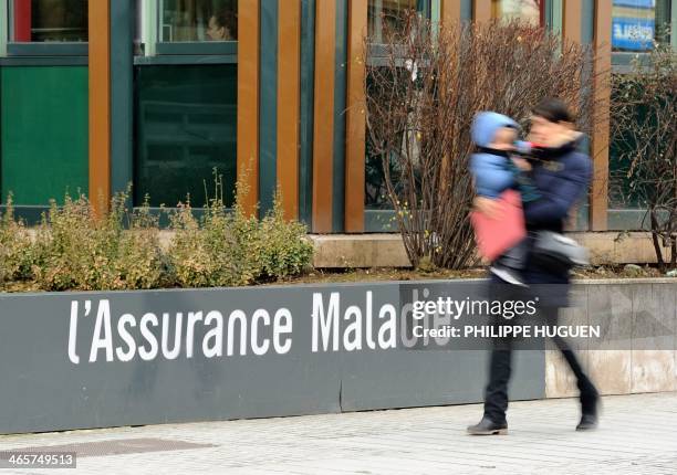 Woman and a child walk in front of the French medical care "L'Assurance Maladie" building on January 29, 2014 in Lille. AFP PHOTO PHILIPPE HUGUEN /...