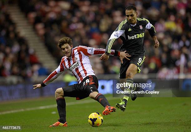 Marcos Alonso of Sunderland is tackled by Peter Odemwingie of Stoke City during the Premier League match between Sunderland and Stoke City at Stadium...