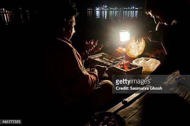 Mobile shop in boat is selling eatables like barbecued kebabs on the Dal lake at night.