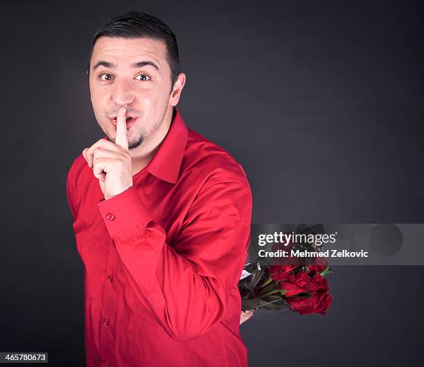 young man with flowers saying shhh - red shirt stock pictures, royalty-free photos & images