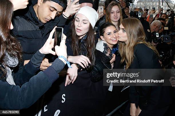 Cara Delevingne poses for photographs with fans as she attends the Yves Saint Laurent Beauty event at Galeries Lafayette on March 10, 2015 in Paris,...